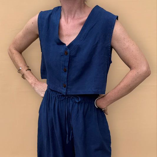 Person wearing a blue sleeveless top and wide-leg pants against a beige background