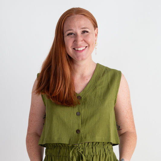 Woman wearing a green sleeveless top and pants against a white background