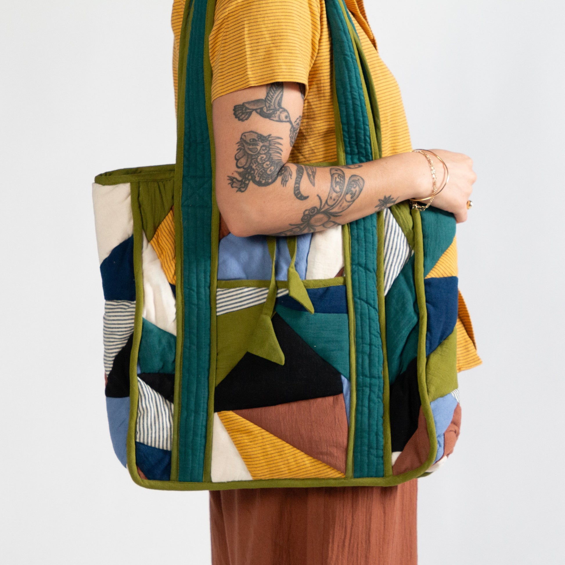 Person holding a colorful quilted bag against a white background