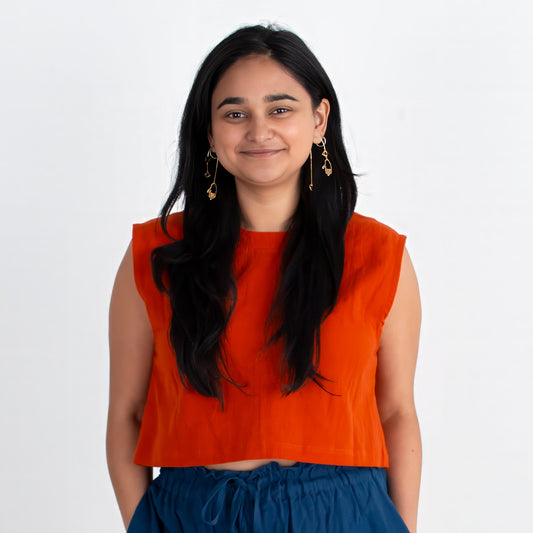 Woman wearing an red top and blue pants standing on a white background