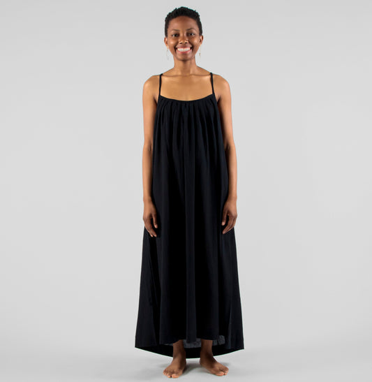 Woman wearing a black dress standing on a white background in a studio setting