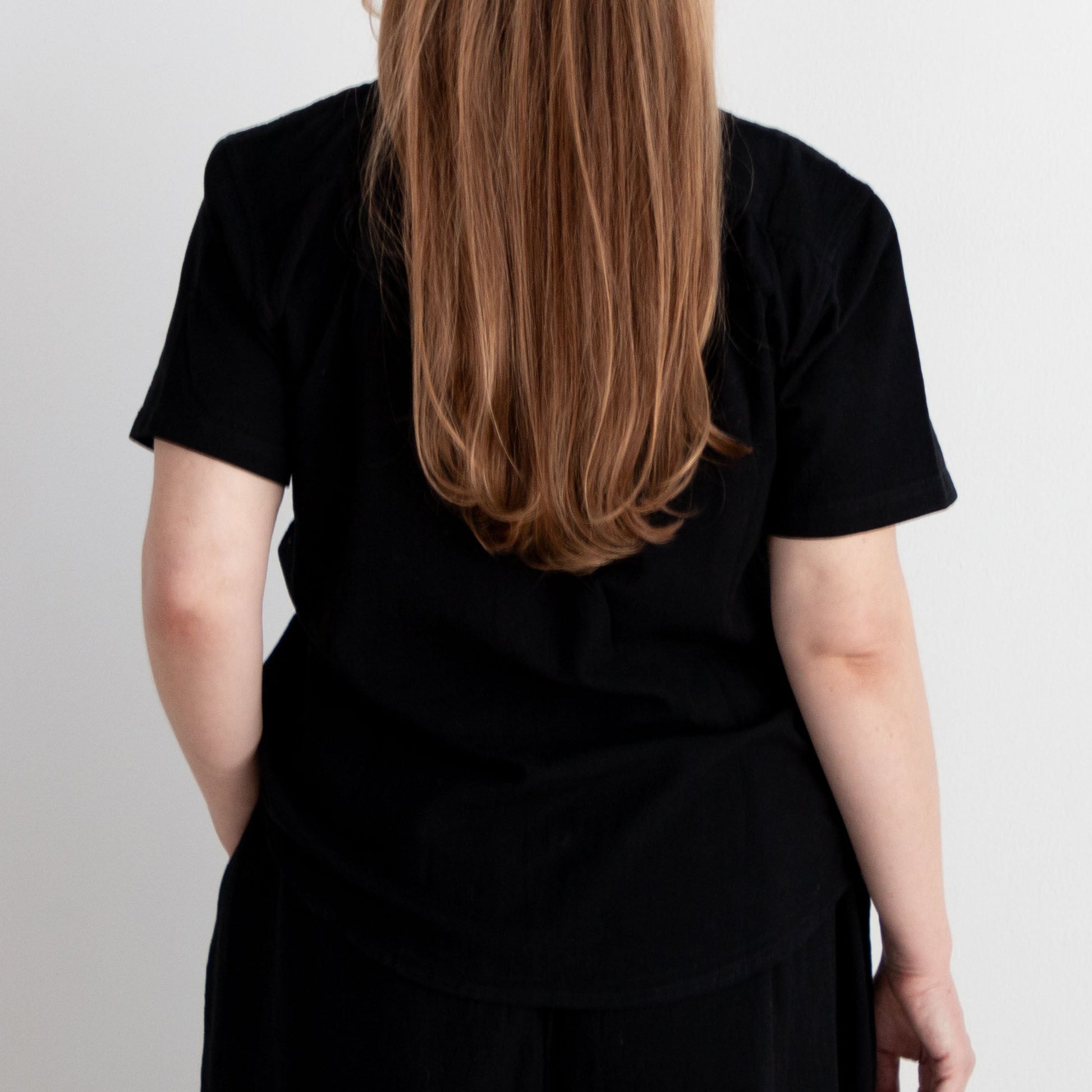 Person wearing a black outfit standing against a white background