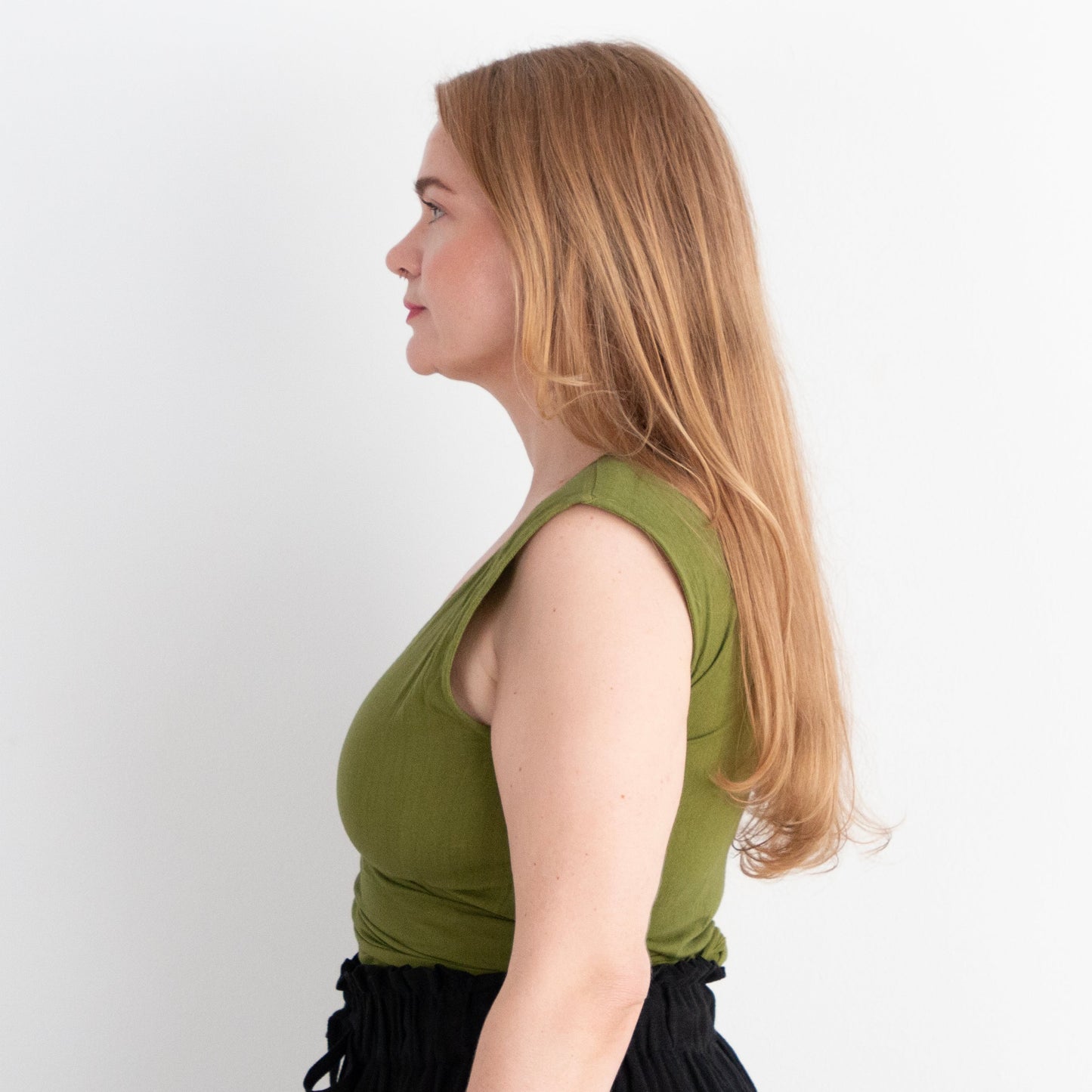 Woman wearing a green top and black skirt on a white background