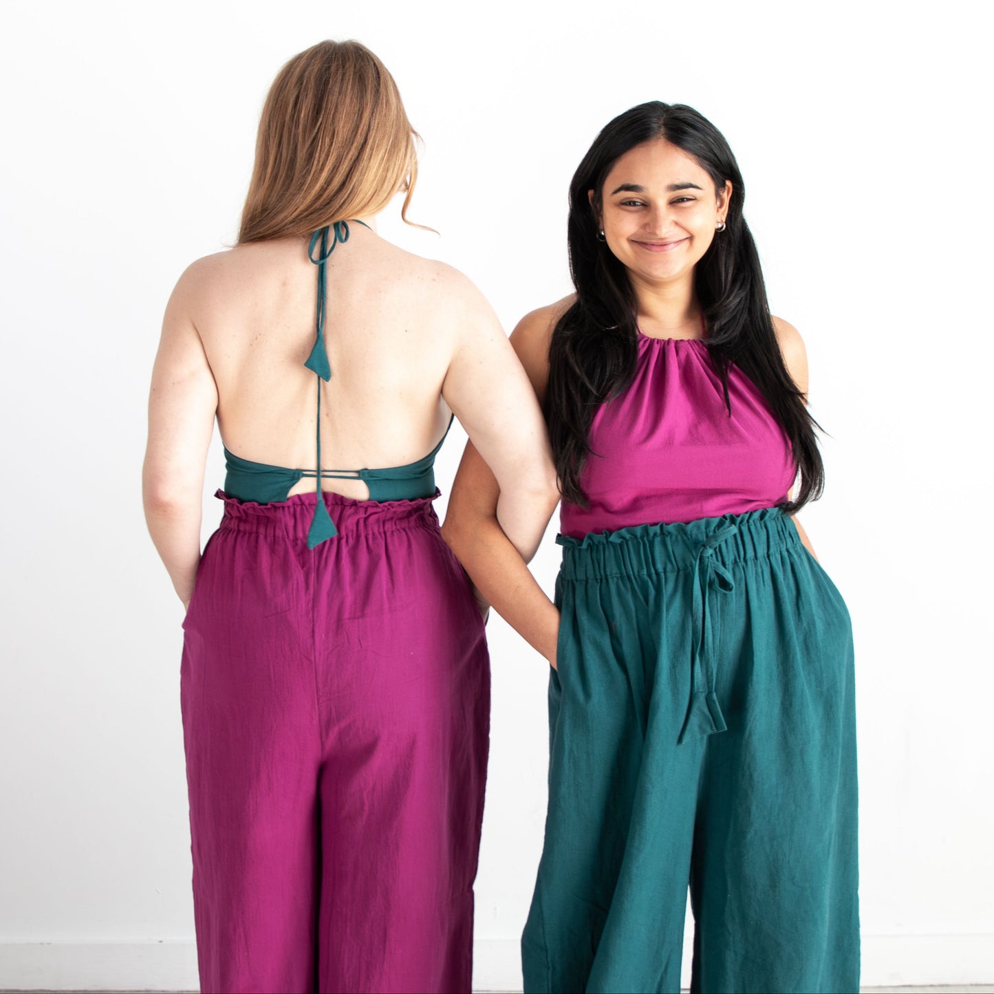 Two women wearing matching outfits with one facing away and the other facing forward on a white background.