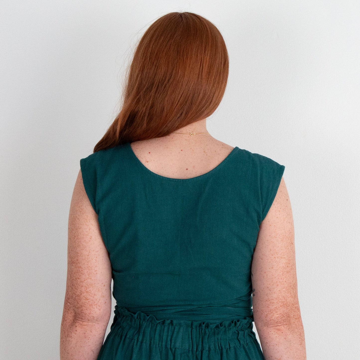 Teal top worn by a person on a plain background