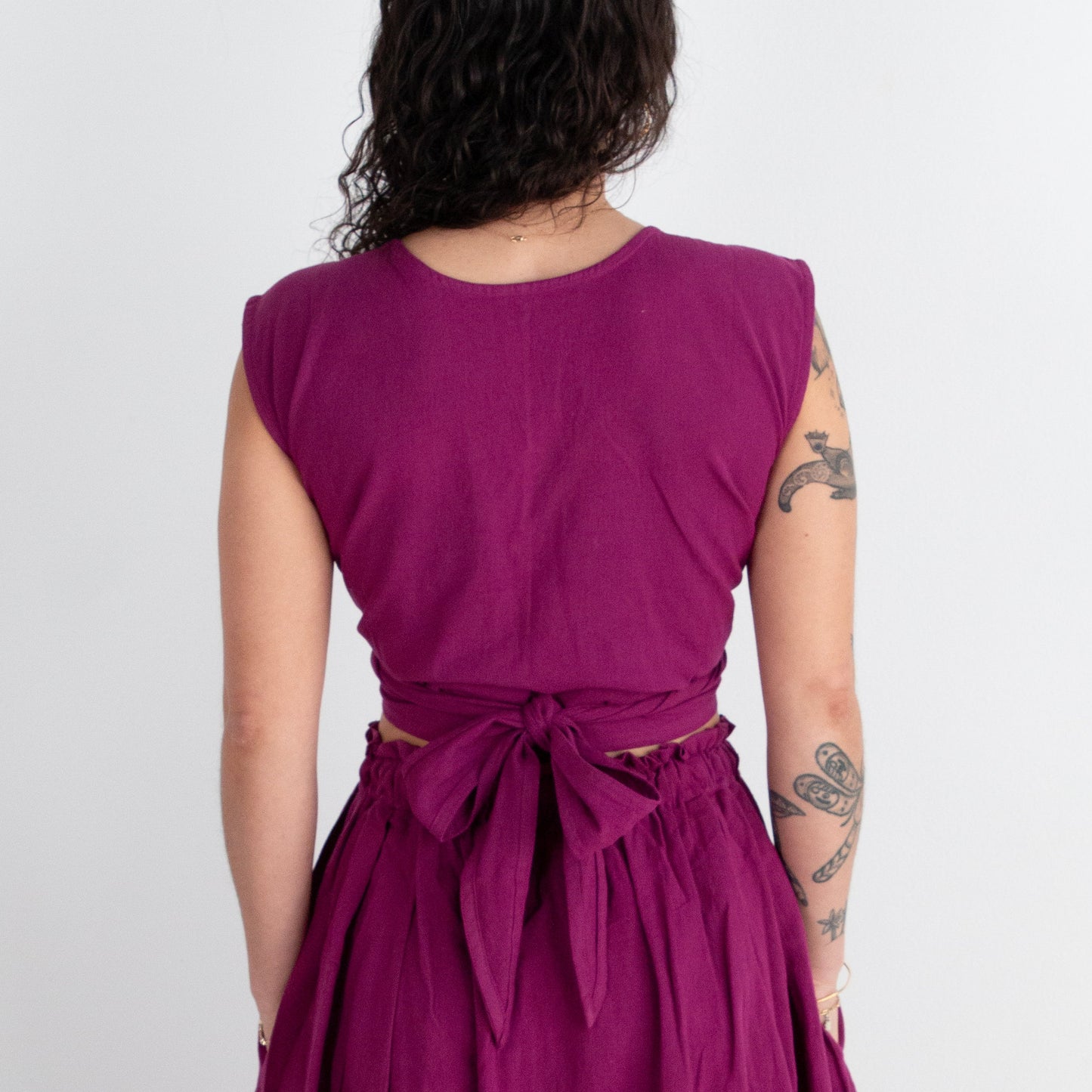 Person wearing a purple top and skirt with a white background