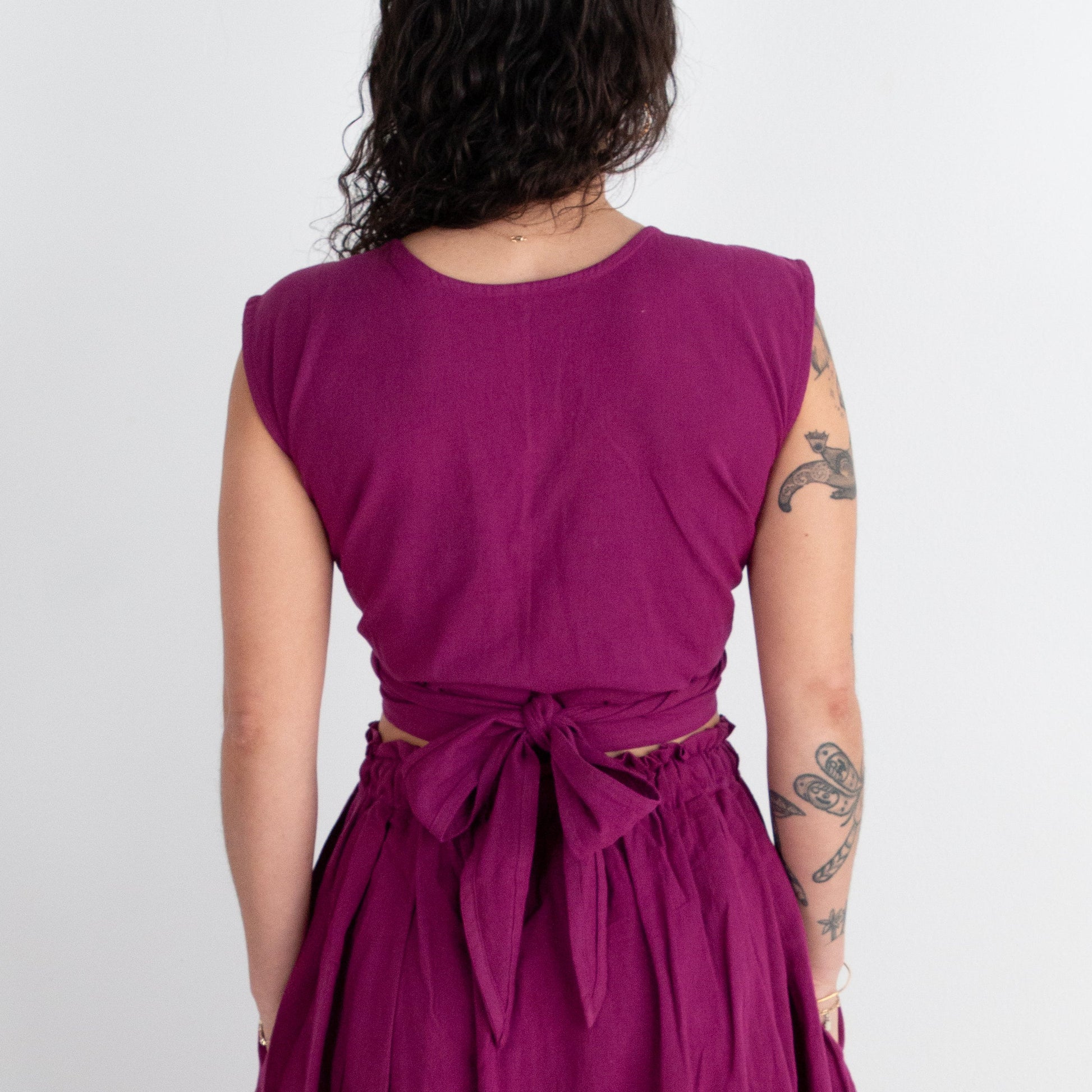 Person wearing a purple top and skirt with a white background